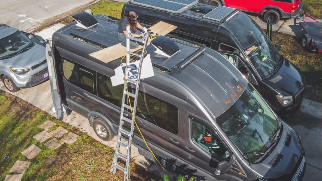 Photo is from an aerial view looking down on a Ford Transit campervan. We are installing two Maxxair fans to use as our van life air conditioning. One fan is installed in the very front of our roofline with the second being installed at the rear of the van.