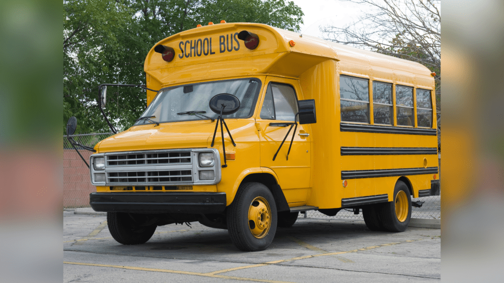 yellow short school bus with a van front parked in a parking lot