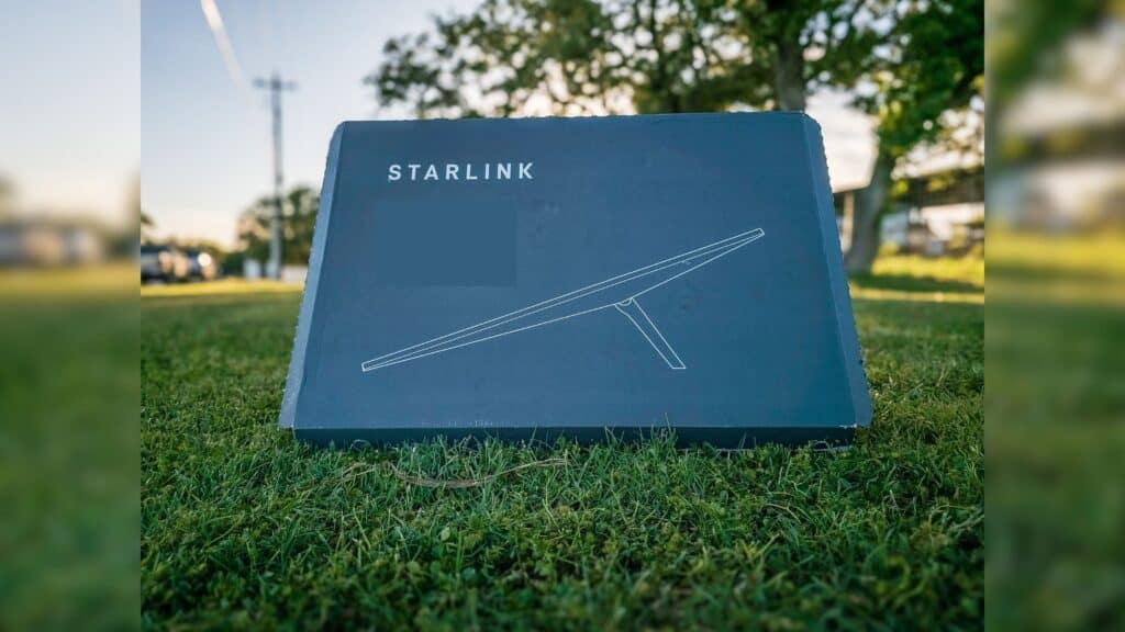 A gray Starlink Box that the dish is shipped in sitting in a green grassy field