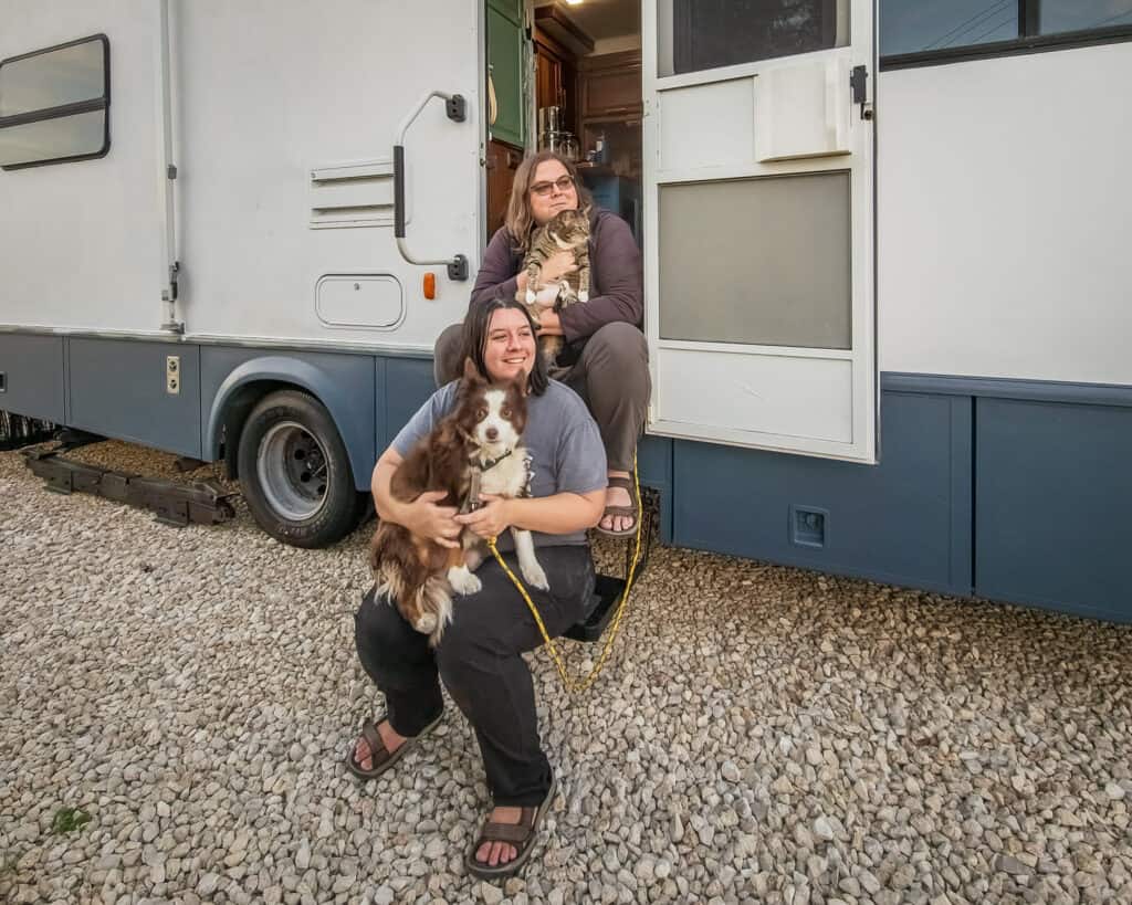 Morgan & Hannah sitting on the steps to their RV with their cat Honey and dog Odie